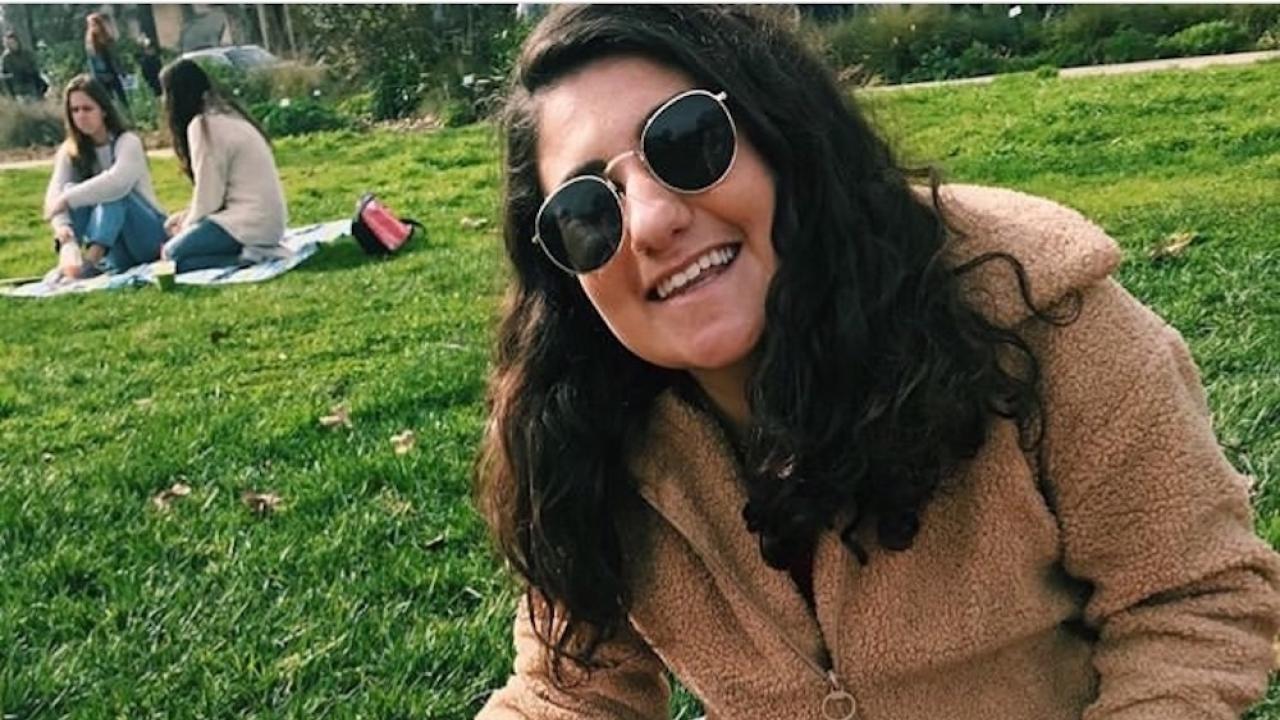 Anna Fox poses in front of a big meal of food at a farmers market at UC Davis. 