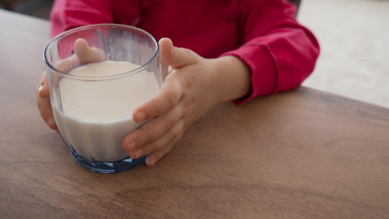 Child's hands hold a class of milk