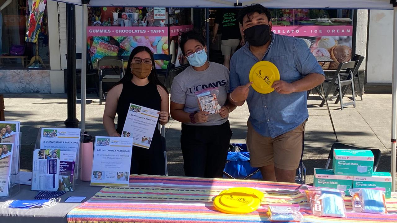 Three people hand out flyers at an outreach event.