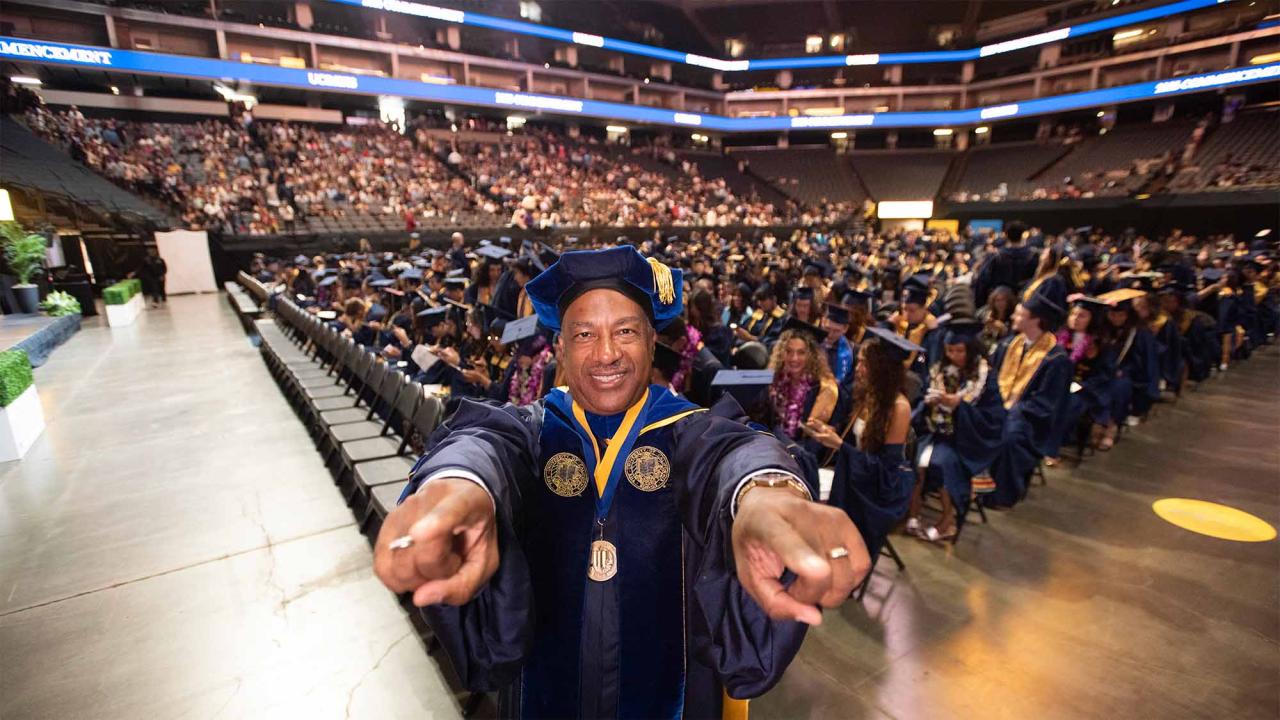 Chancellor Gary S. May poses for a photo with graduates at a commencement ceremony in Golden 1 Center