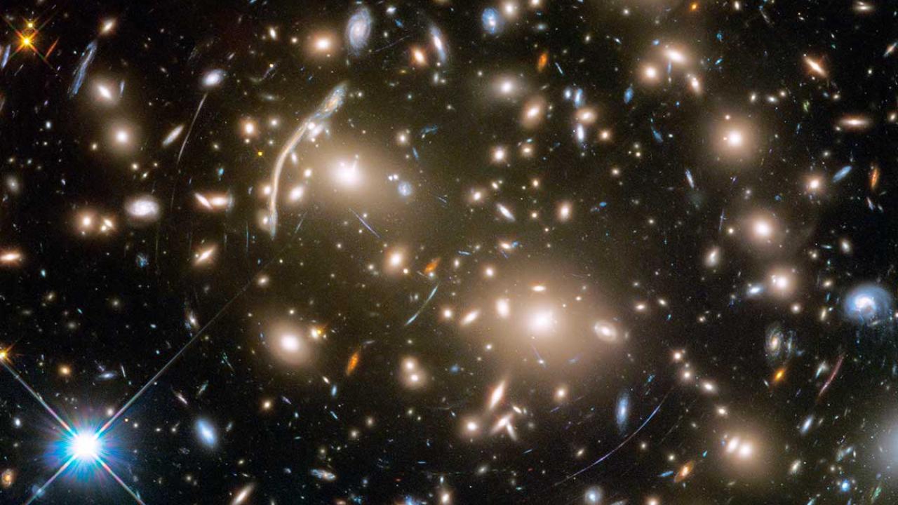A field of stars and galaxies, some distorted in shape.