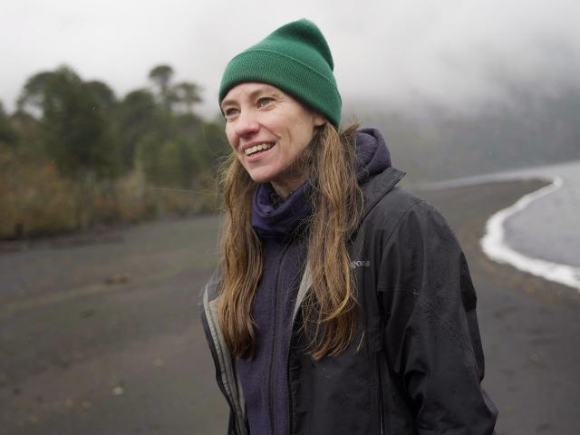 Toby Kiers stands at water's edge in coat and hat