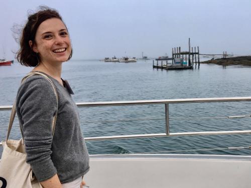 Woman smiling at camera with calm ocean in background