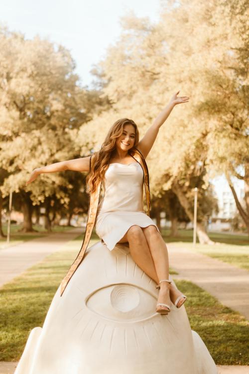 Olivia-Alexis Sanchez posing on top of an Egghead with her graduation stole.