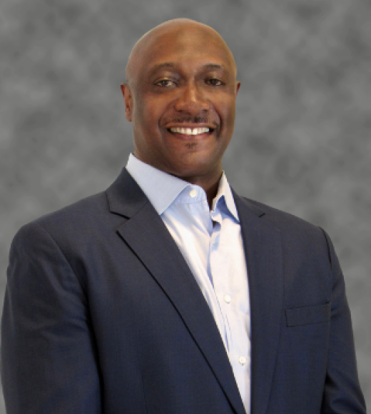Smiling man in a suit with a gray background.