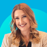 Smiling redheaded woman headshot, beige blazer, teal circular background.