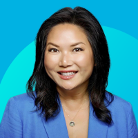 Headshot of smiling Asian woman in blue blazer on teal gradient background