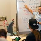 Student standing in front of white board full of engineering calculations.