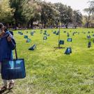 Two people take grocery bags, which are spaced wide apart on the Quad.