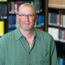 Ari Kelman stands in front of books.