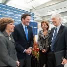 Four people smiling and conversing while standing 