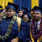 Men sit at commencement ceremony.