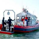 Photo: two divers standing at the end of a boat on the ocean