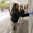 Two female Aggie Hosts, in uniform, checking doors to be sure they are locked.