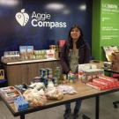 Table of food at Aggie Compass, with student standing behind.