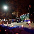 Man talks to audience of people holding candles.