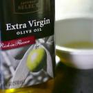 A bowl of olive oil with garnish of leaves and red berries