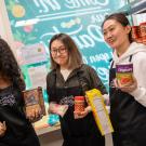 Three student interns, holding food items at the Pantry.