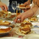 People serve slices of pie from a table.