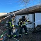 Three firefighters spray water on a building.