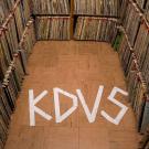 Photo: stacks of records with KDVS spelled on the floor with tape