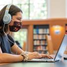 Student studies in library with laptop