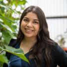 A student poses smiling beside green vines at UC Davis.