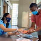 One student pumps hand sanitizer into the hands of another student