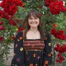 Woman stands in front of a wall of flowers