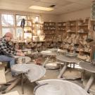 A person at a pottery wheel, shaping clay in a pottery studio.