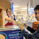 A Coffee House worker serves food in a blue reusable container to a student at UC Davis. 