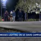 Group walks along path, under overhead lamp, to check on lighting safety