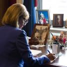 Woman sits at desk writing on paper