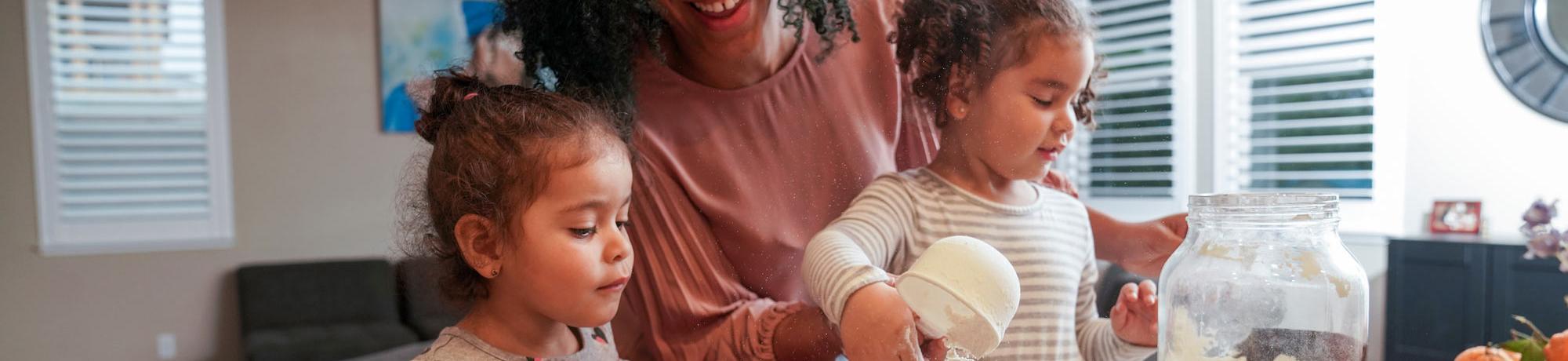 A mother cooks with her two young daughters