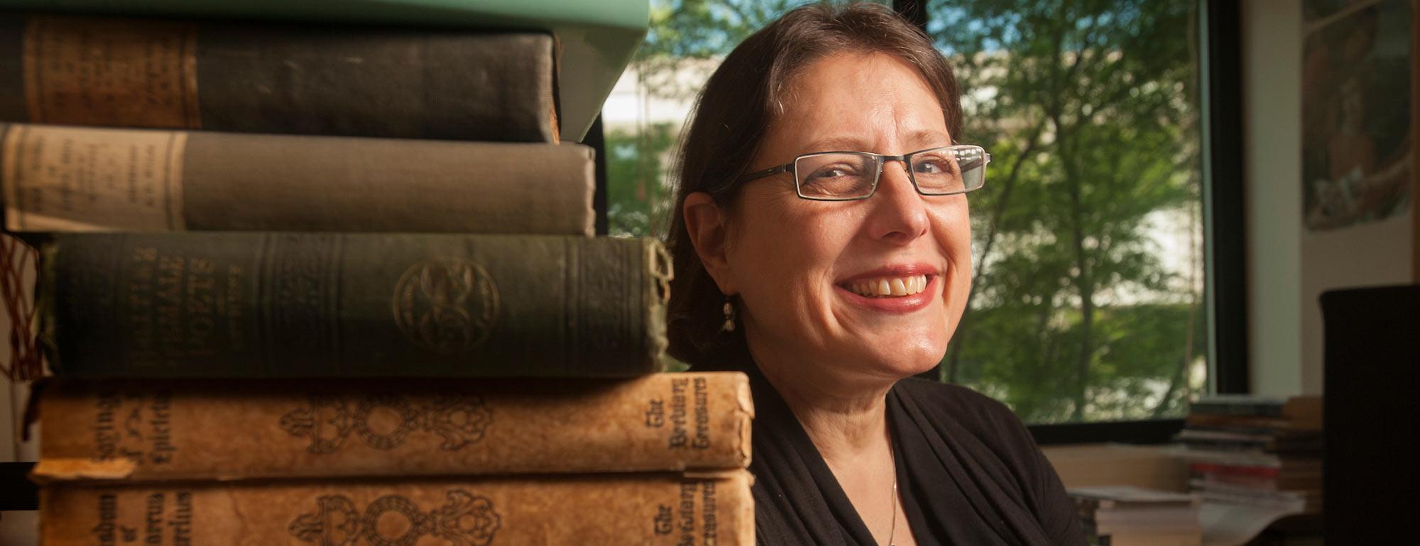 A professor of 18th century literature poses next to her book collection