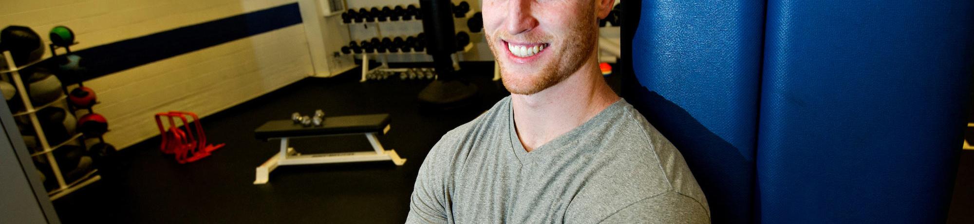 A male student poses next to exercise equipment