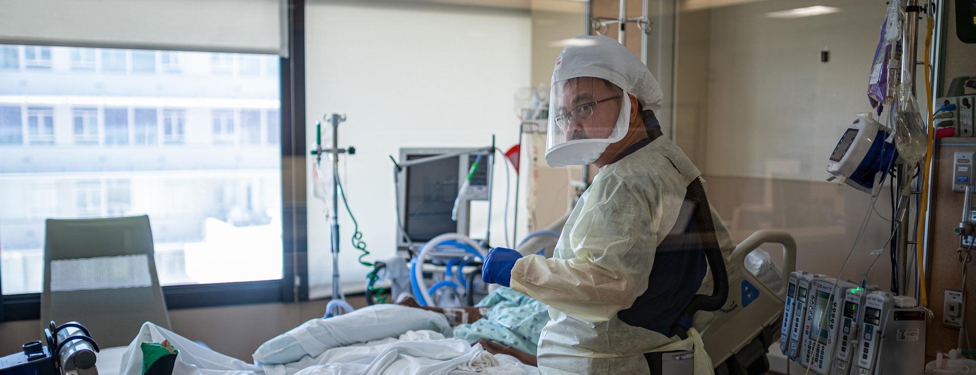 A nurse in full hazmat attends to a patient