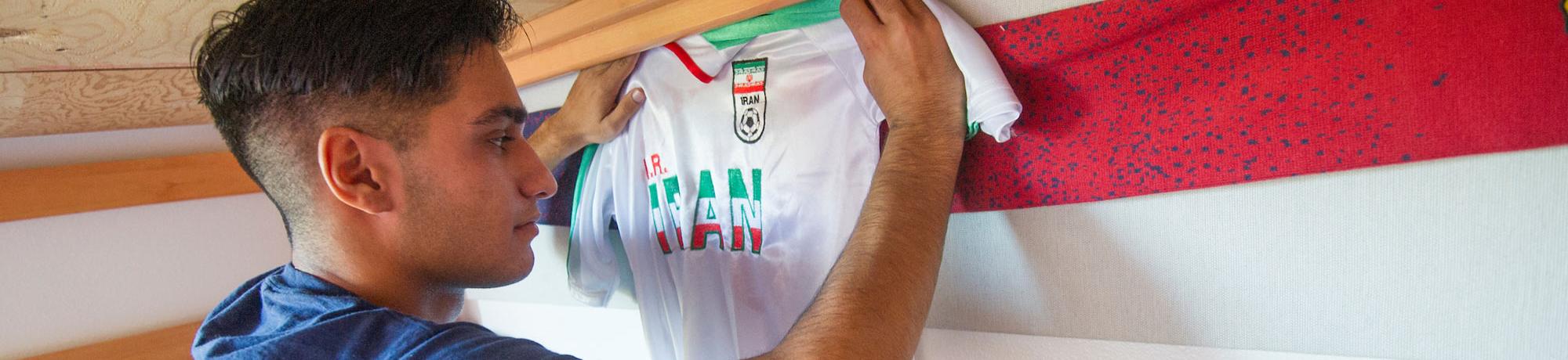 A student pins up an Iranian National Soccer team jersey in his dorm room