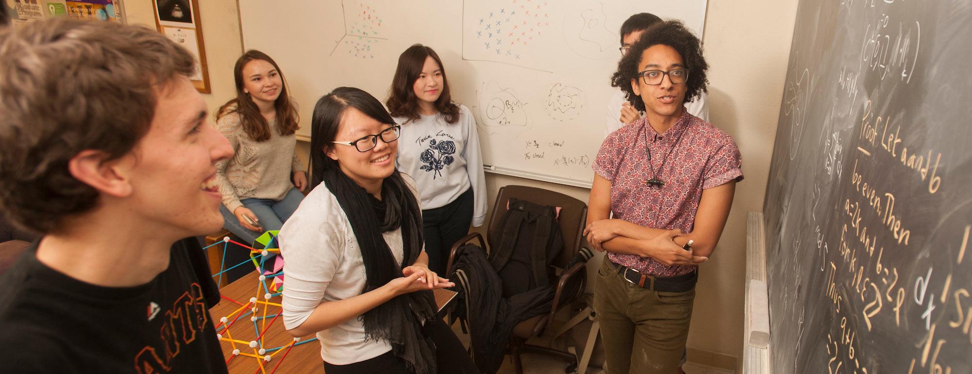 A group of math students considering a complex problem on a blackboard