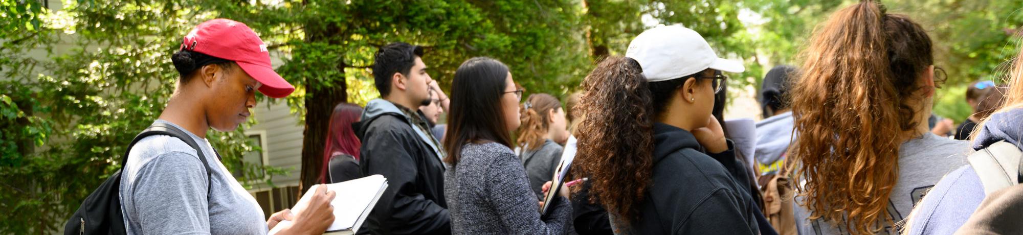 students in a landscape design class outside, one student taking notes