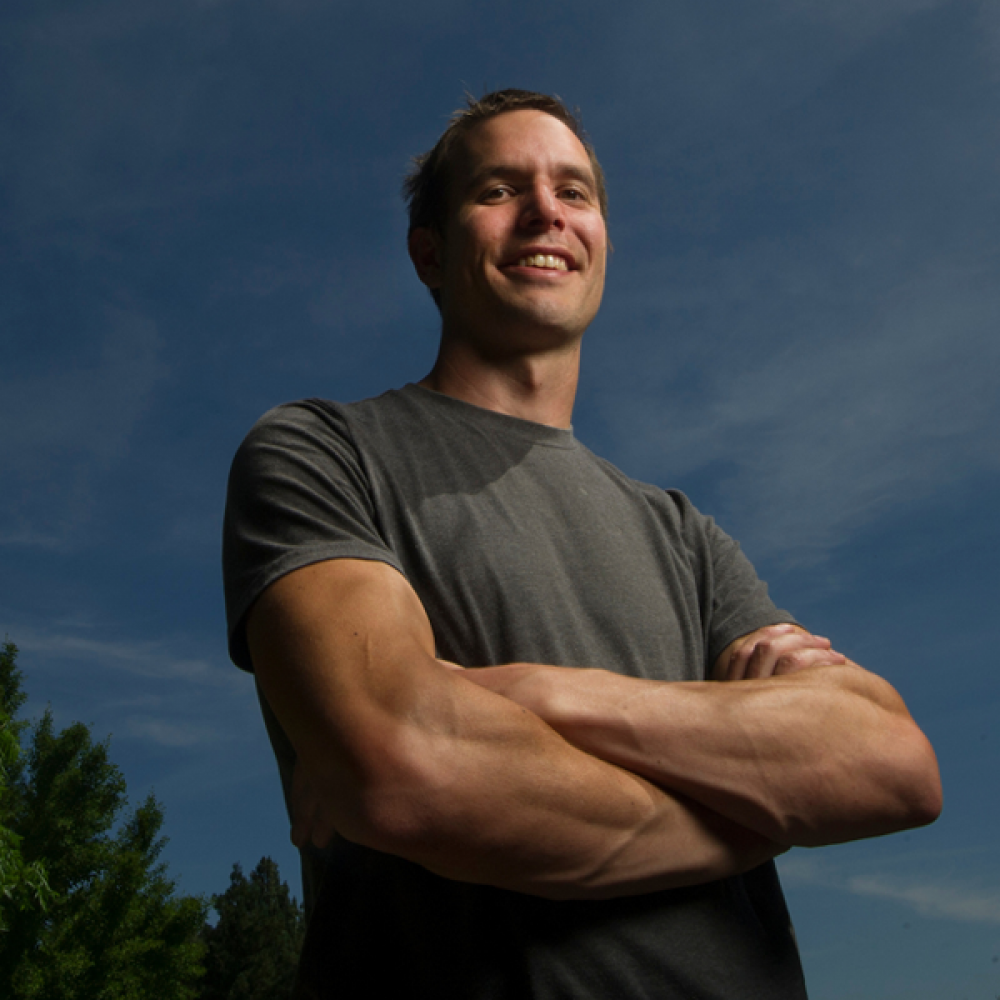 A man smiling with his arms crossed.