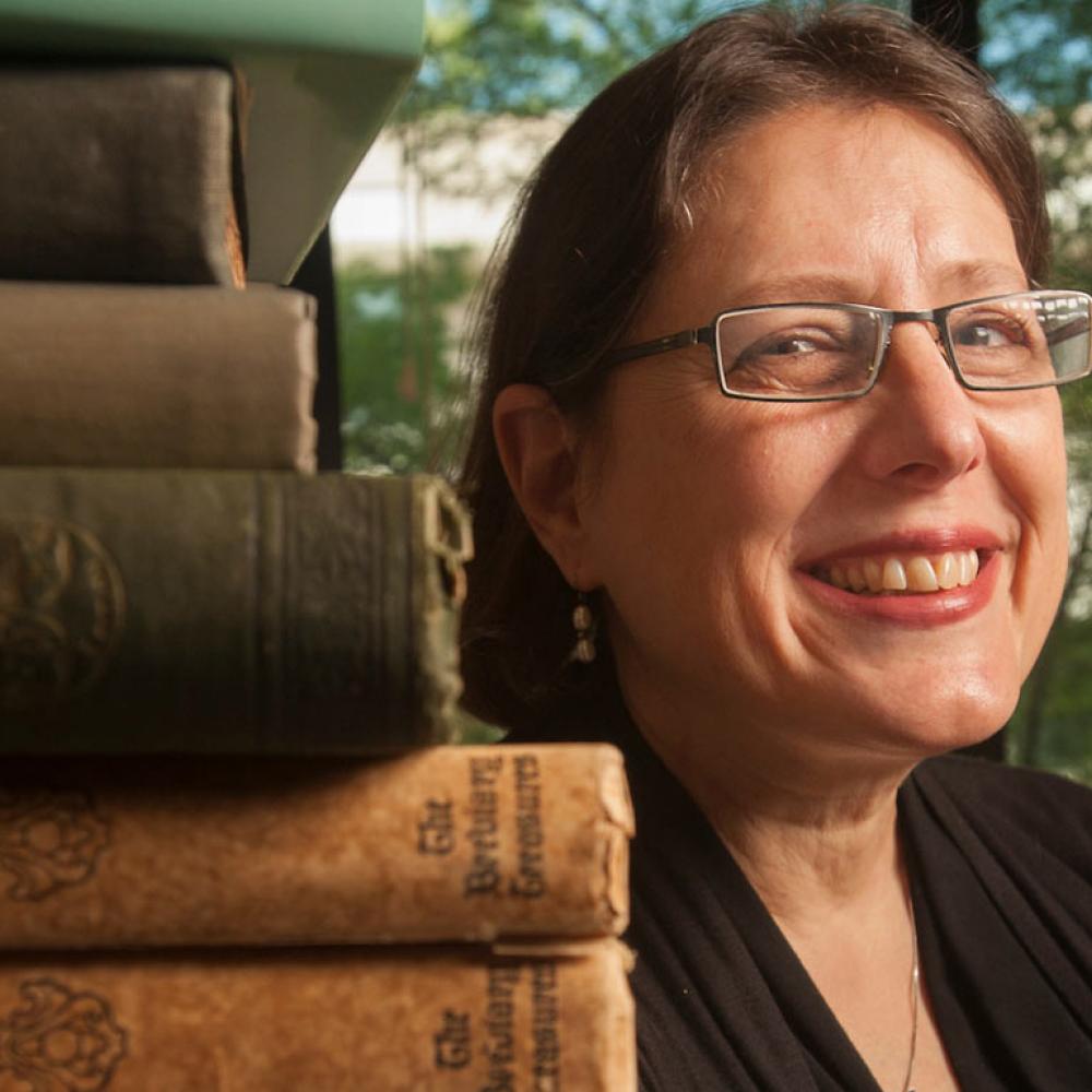 A professor of 18th century literature poses next to her book collection