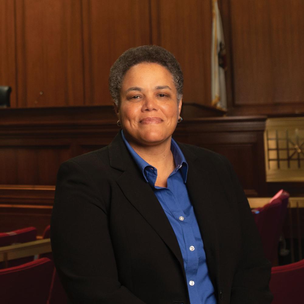 Portrait of a woman standing in a large courtroom.