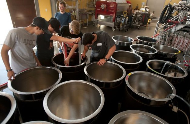 Students inspecting metal barrels 