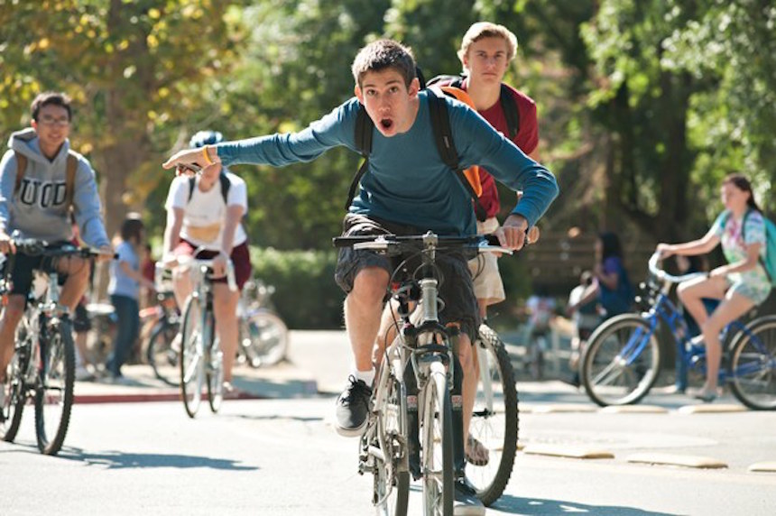 Student riding bike amongst other students also on bikes