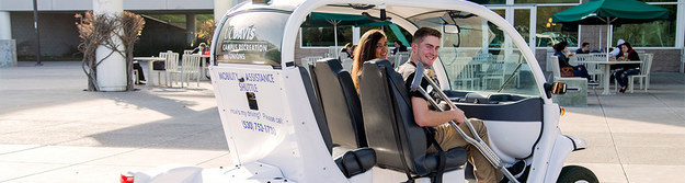 A mobility assistance golf cart giving a ride to a student with crutches