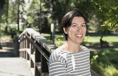 A woman stands among campus greenery