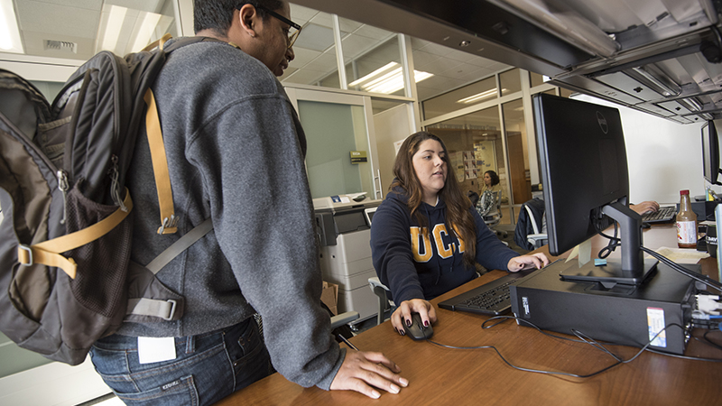 Two students at a computer talk